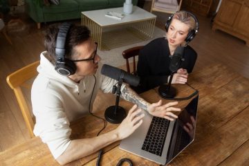 Equipamentos essenciais para começar uma web rádio: computador, microfone, fones de ouvido e mesa de mixagem em um estúdio com isolamento acústico.